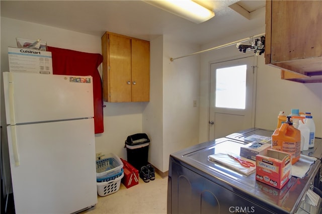 kitchen with freestanding refrigerator, washer / dryer, and brown cabinetry