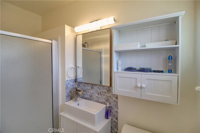 bathroom featuring a shower with door, toilet, backsplash, and vanity