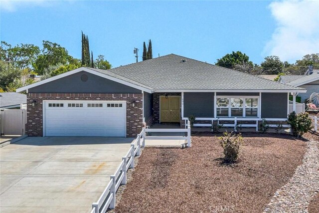 ranch-style house featuring brick siding, driveway, a garage, and fence
