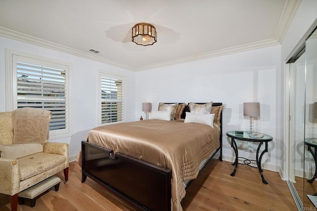 bedroom featuring baseboards, ornamental molding, wood finished floors, and visible vents