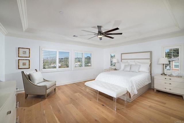 bedroom with crown molding, light wood-style floors, and a tray ceiling