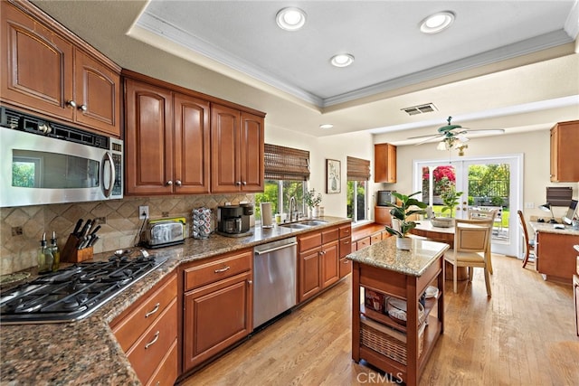 10 Cambridge Ct, Coto De Caza, CA 92679 - kitchen with stainless steel appliances, ornamental molding, a tray ceiling, tasteful backsplash, and light wood-style floors