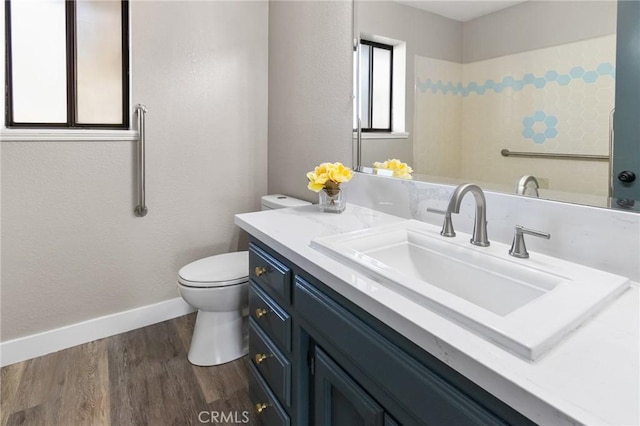 bathroom with toilet, baseboards, wood finished floors, and vanity