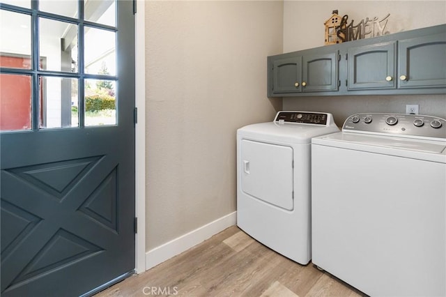 washroom featuring separate washer and dryer, baseboards, light wood finished floors, and cabinet space