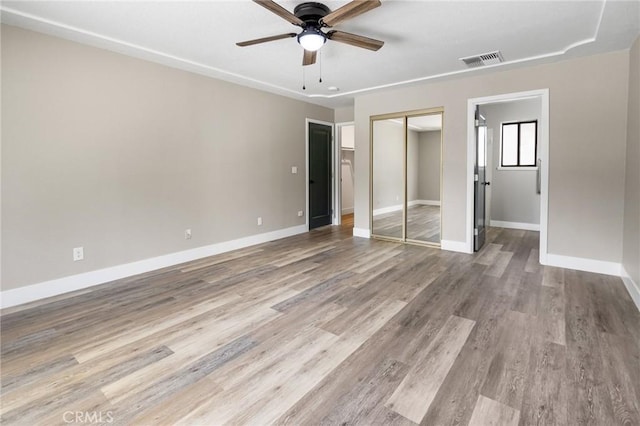 unfurnished bedroom featuring visible vents, baseboards, wood finished floors, and a closet