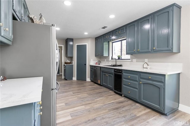 kitchen with visible vents, appliances with stainless steel finishes, a sink, baseboards, and light wood-style flooring