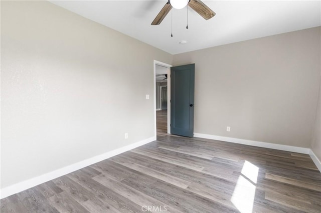 empty room with baseboards, a ceiling fan, and wood finished floors