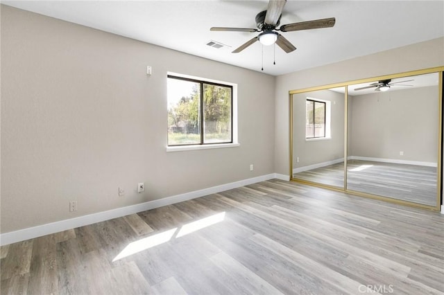 unfurnished bedroom featuring visible vents, baseboards, a closet, and light wood-type flooring