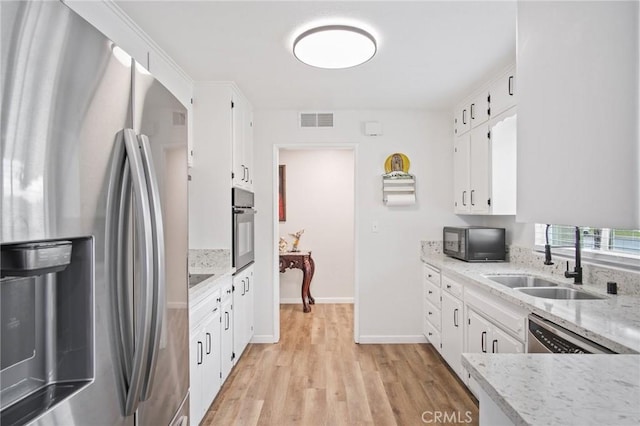kitchen with visible vents, a sink, black appliances, light wood-style flooring, and white cabinetry