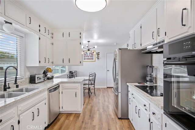 kitchen with a sink, black appliances, light wood-style floors, white cabinetry, and under cabinet range hood