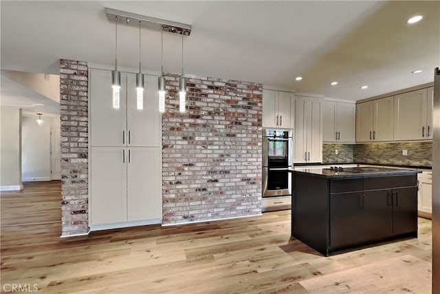 2100 Sherwood Ave Unit A, Modesto, CA 95350 - kitchen featuring light wood-style flooring, stainless steel double oven, dark countertops, a kitchen island, and backsplash