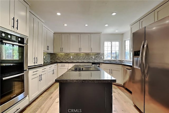 2100 Sherwood Ave Unit A, Modesto, CA 95350 - kitchen featuring a sink, a kitchen island, appliances with stainless steel finishes, decorative backsplash, and dark stone counters