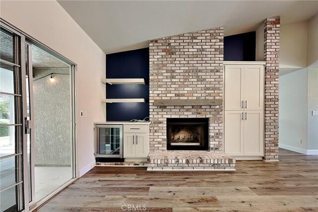 2100 Sherwood Ave Unit A, Modesto, CA 95350 - unfurnished living room featuring baseboards, vaulted ceiling, a brick fireplace, and light wood finished floors