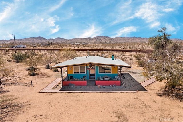 back of property featuring a rural view, a mountain view, view of desert, and covered porch