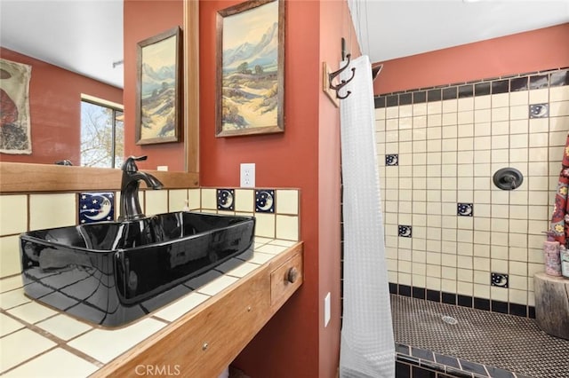 full bathroom featuring a tile shower and a sink