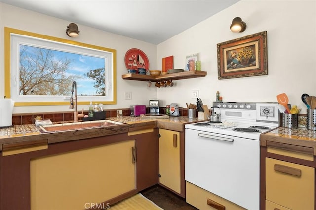 kitchen with a sink, tile counters, and white range with electric stovetop