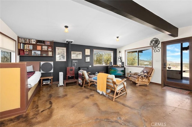 living area with vaulted ceiling with beams, a wood stove, and concrete flooring