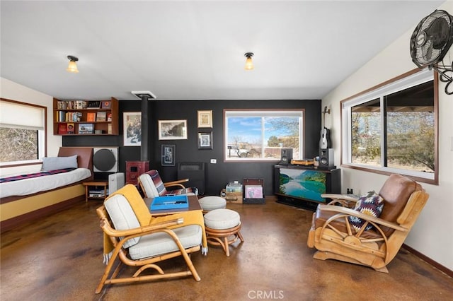 sitting room with finished concrete floors, a wood stove, and plenty of natural light