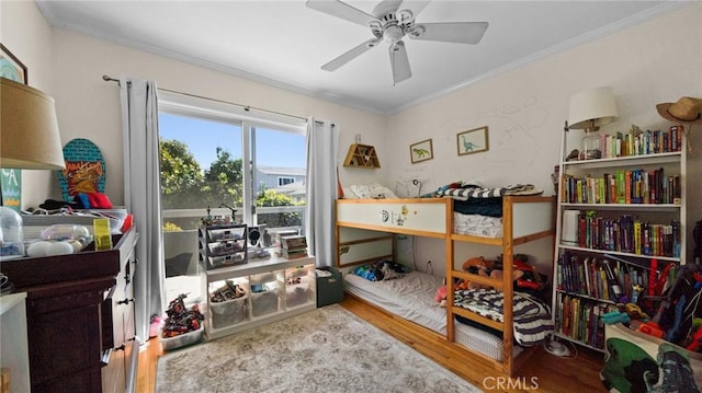 bedroom featuring crown molding, wood finished floors, and a ceiling fan