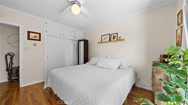 bedroom with baseboards, ornamental molding, wood finished floors, and ceiling fan