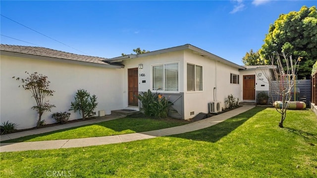view of front of house with a front lawn, stucco siding, ac unit, and fence