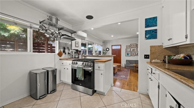 kitchen with white cabinetry, light tile patterned floors, stainless steel range with gas cooktop, and backsplash