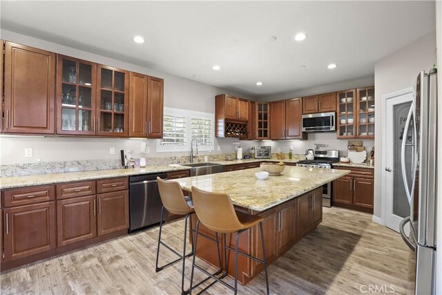 13083 Via Tuscany, Riverside, CA 92503 - kitchen with stainless steel appliances, a sink, a center island, a kitchen bar, and light wood-style floors