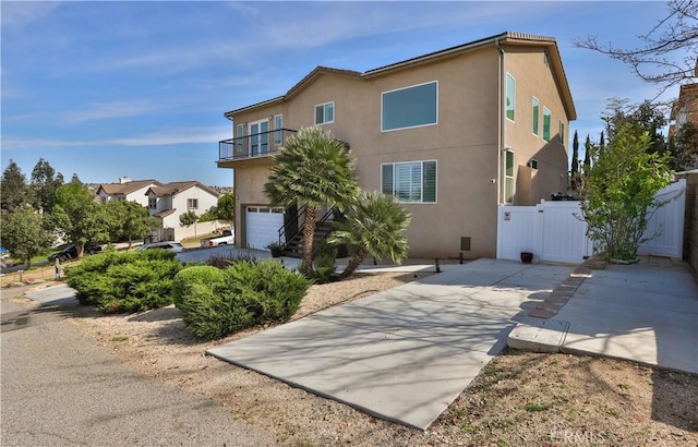 13083 Via Tuscany, Riverside, CA 92503 - view of side of property featuring stucco siding, a balcony, an attached garage, and concrete driveway