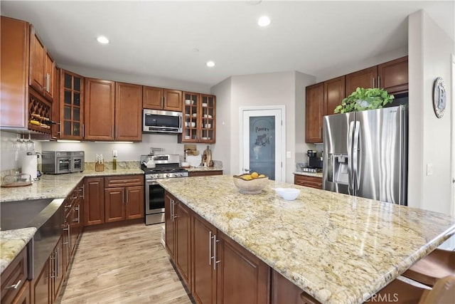 13083 Via Tuscany, Riverside, CA 92503 - kitchen with stainless steel appliances, a center island, light wood-style flooring, recessed lighting, and light stone countertops