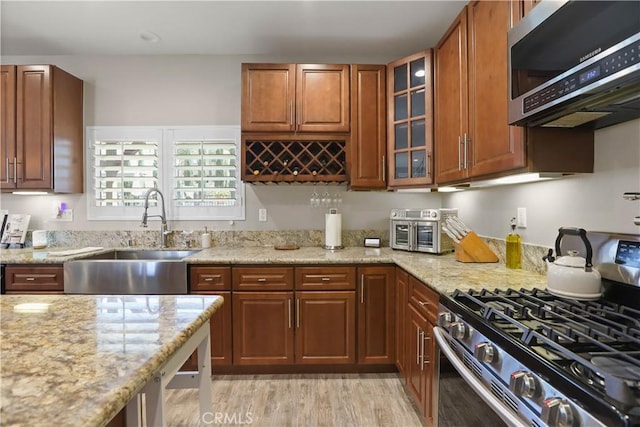 13083 Via Tuscany, Riverside, CA 92503 - kitchen with stainless steel appliances, a sink, light stone counters, glass insert cabinets, and brown cabinets