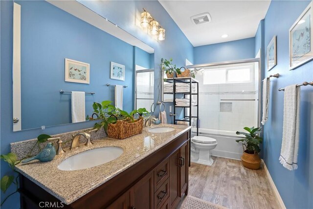 13083 Via Tuscany, Riverside, CA 92503 - full bathroom featuring toilet, double vanity, wood finished floors, bath / shower combo with glass door, and baseboards