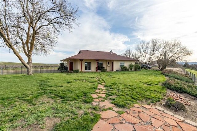 rear view of property with fence and a lawn