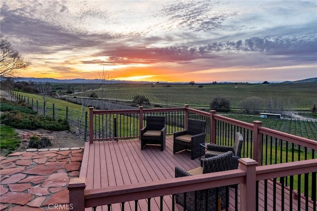deck at dusk featuring a mountain view and a rural view