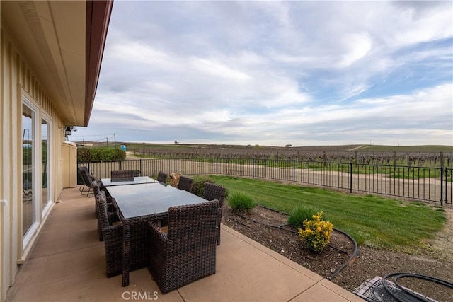 view of patio / terrace with outdoor dining space, fence, and a rural view