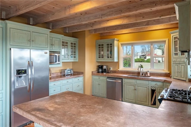 kitchen with green cabinets, beamed ceiling, a sink, and stainless steel appliances