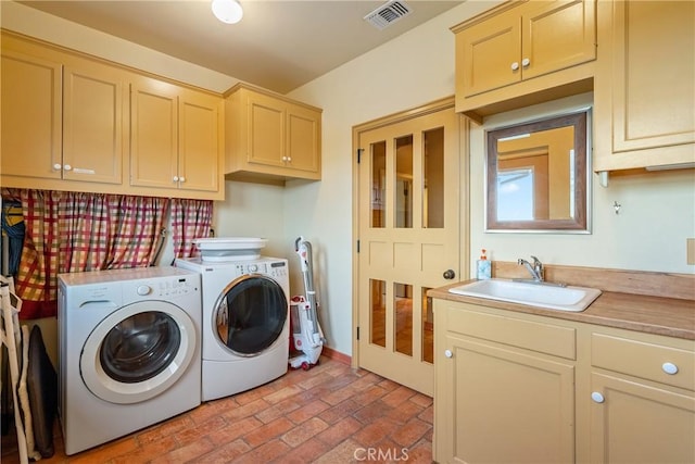 clothes washing area featuring a sink, brick floor, visible vents, washer and dryer, and cabinet space