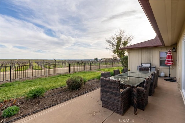 view of patio / terrace featuring a rural view, outdoor dining area, and fence