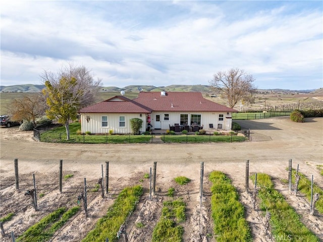 rear view of house featuring a fenced front yard, a rural view, and board and batten siding