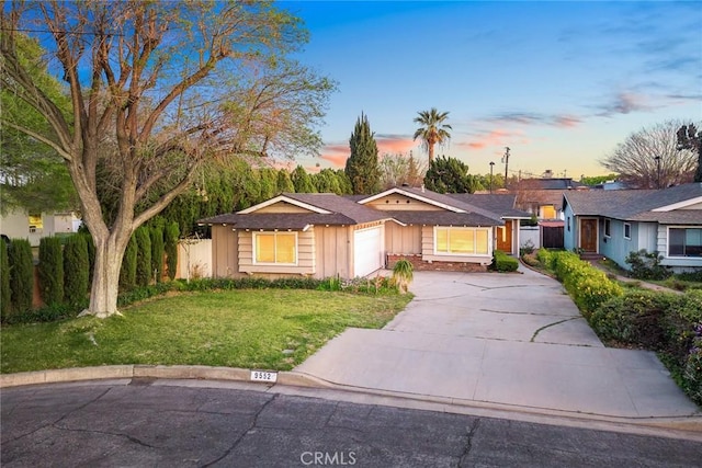 ranch-style house with a lawn, driveway, an attached garage, and fence