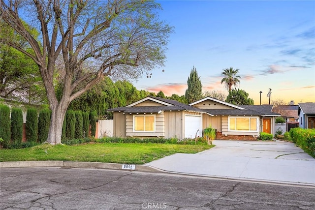 ranch-style home with a front lawn, driveway, fence, and a garage