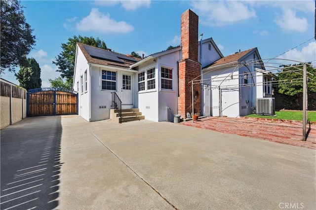 11330 Whitley St, Whittier, CA 90601 - back of house with a gate, entry steps, stucco siding, roof mounted solar panels, and a chimney