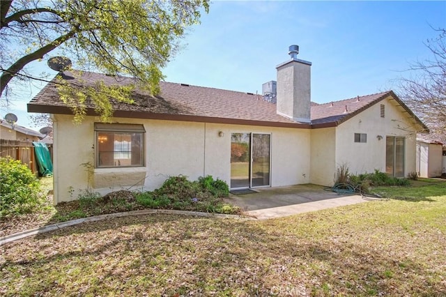 back of property with stucco siding, fence, a lawn, a patio, and a chimney