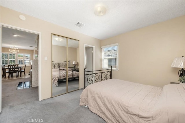bedroom with carpet floors, a closet, a chandelier, and visible vents