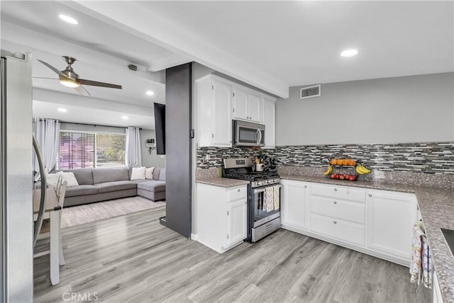 kitchen featuring a ceiling fan, appliances with stainless steel finishes, open floor plan, visible vents, and light wood-style floors