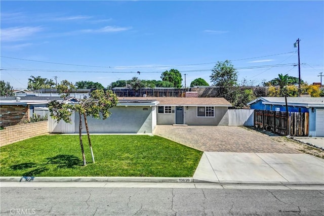 single story home featuring a front yard, stucco siding, fence, and driveway