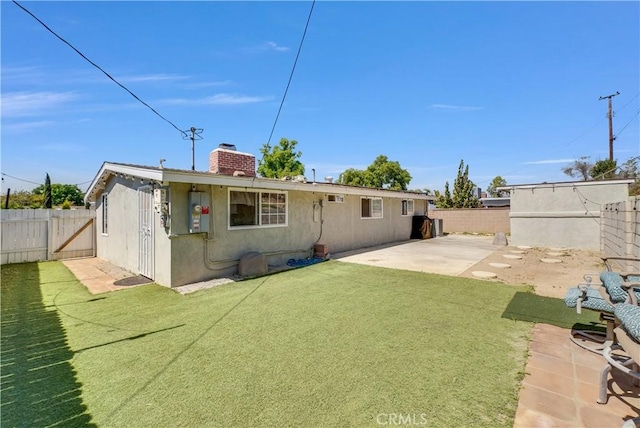 back of house featuring a fenced backyard, a lawn, a patio area, and a chimney