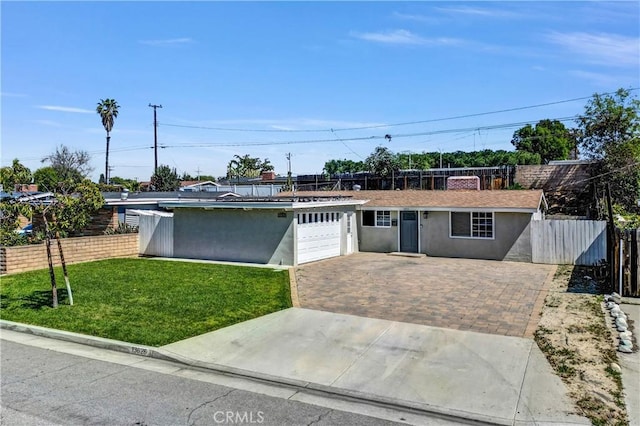 ranch-style house with fence, an attached garage, stucco siding, a front lawn, and driveway