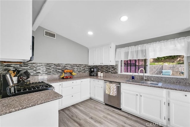 kitchen with stove, tasteful backsplash, stainless steel dishwasher, a sink, and white cabinets