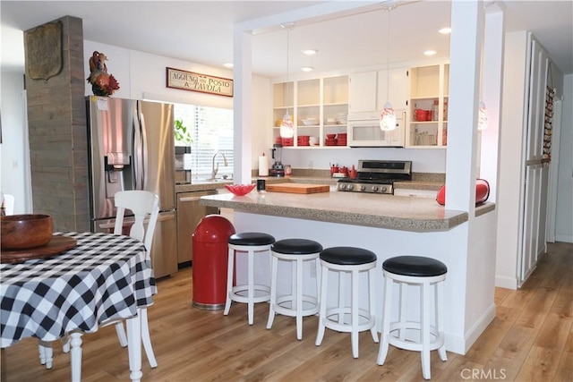 31351 Calle Del Campo, San Juan Capistrano, CA 92675 - kitchen with stainless steel appliances, light wood-style floors, open shelves, a sink, and a kitchen bar