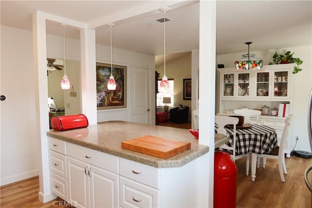 31351 Calle Del Campo, San Juan Capistrano, CA 92675 - kitchen with light wood-type flooring, white cabinets, a ceiling fan, light stone counters, and hanging light fixtures